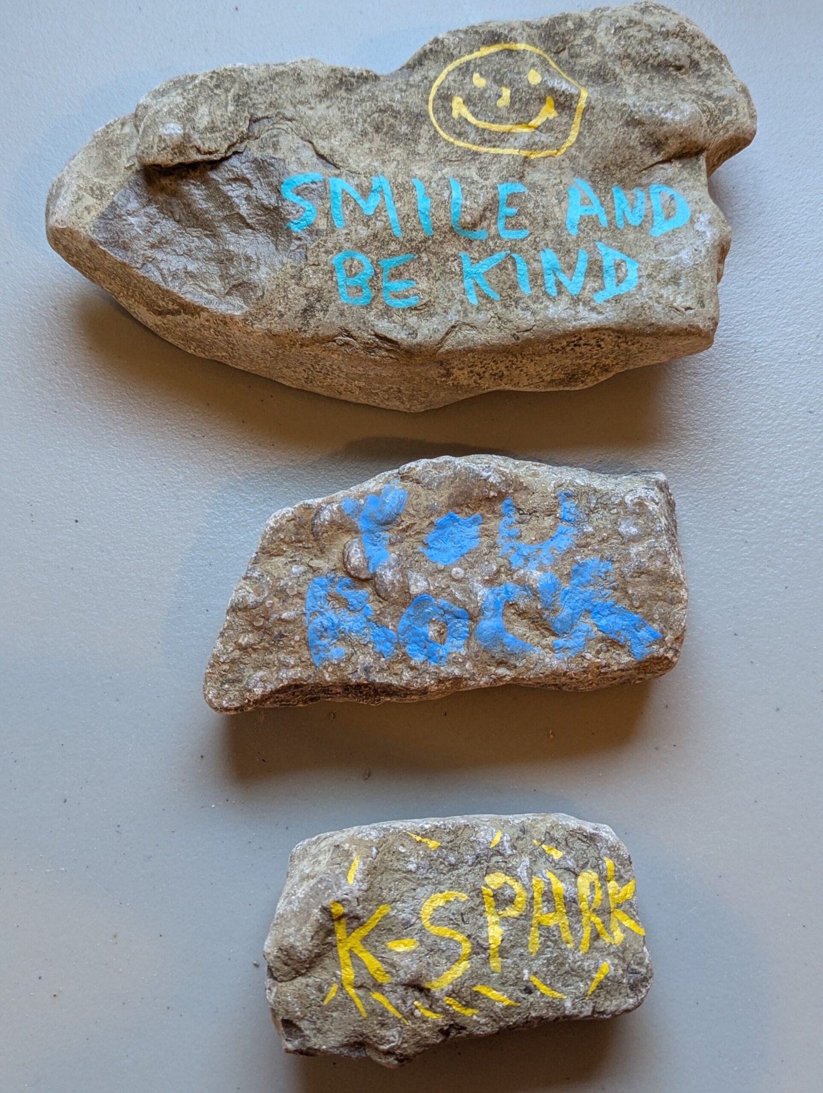 Three Kindness Rocks: Smile and Be Kind, You Rock, and K-Spark