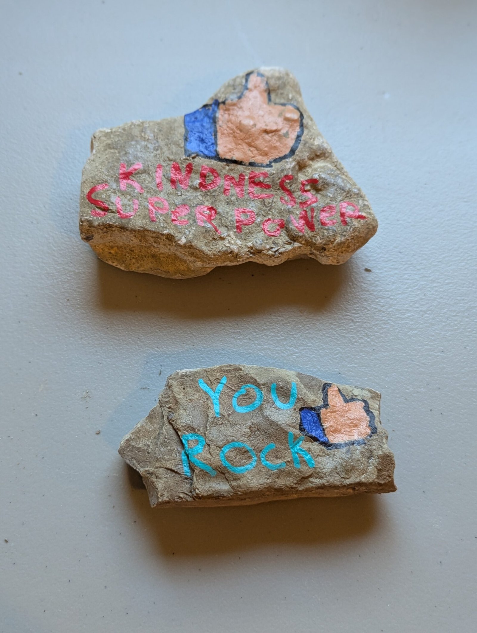 Two Kindness Rocks: Kindness Super Power and You Rock with thumbs-up icons
